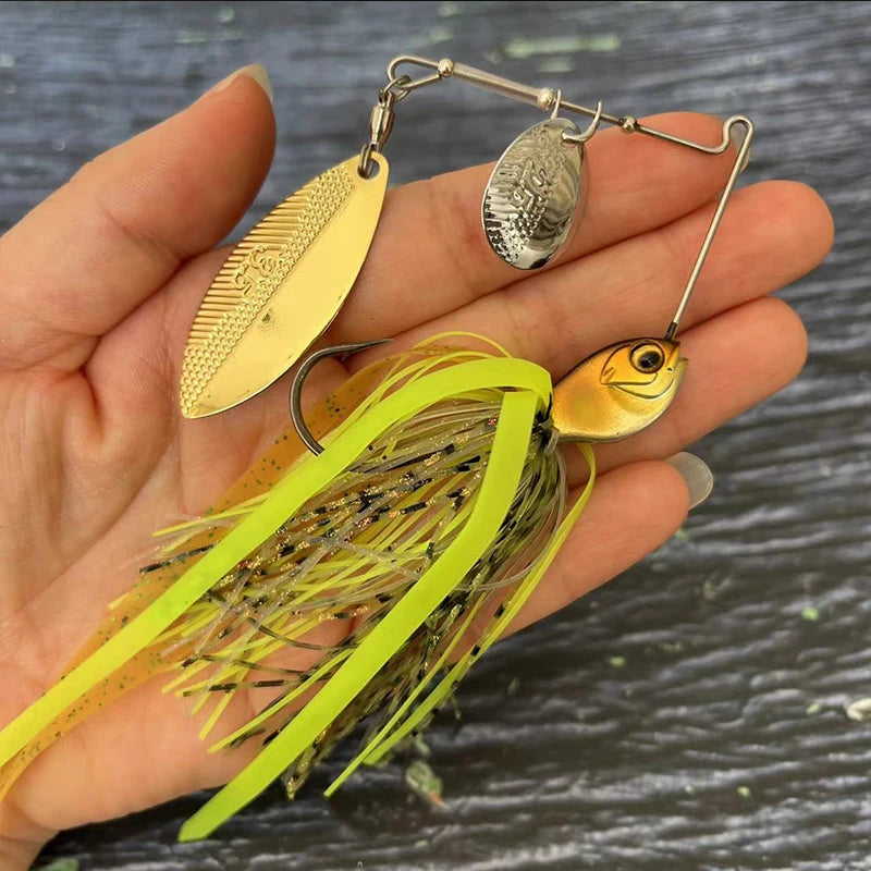 Hand holding a gold and silver spinnerbait fishing lure with yellow skirt and fish-shaped head.
