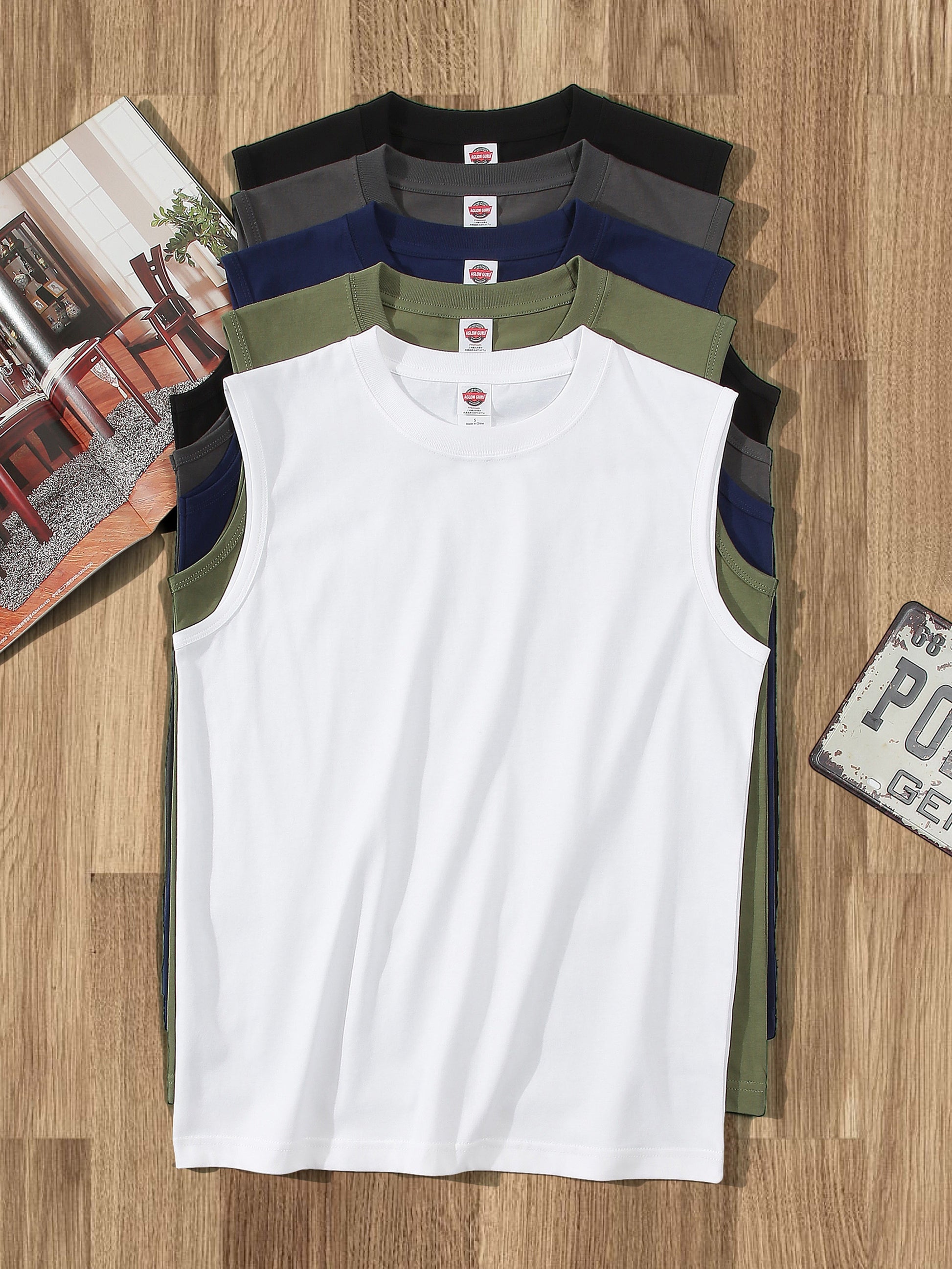 White sleeveless shirt with black, blue, and green accents on a wooden surface.