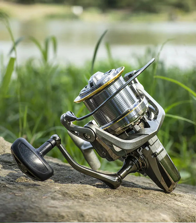 Fishing reel outdoor on rock beside grassy lake shore, durable fishing gear