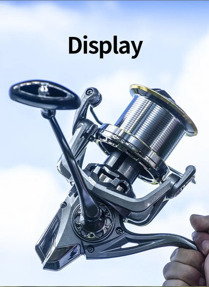 Close-up of a modern metallic fishing reel held outdoors against a blue sky
