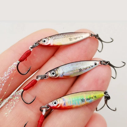 Three colorful fishing lures with treble hooks and realistic fish scale patterns on a hand