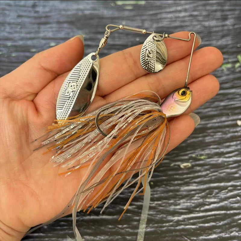 Hand holding a metal fishing lure with spinner blades and orange-silver skirt