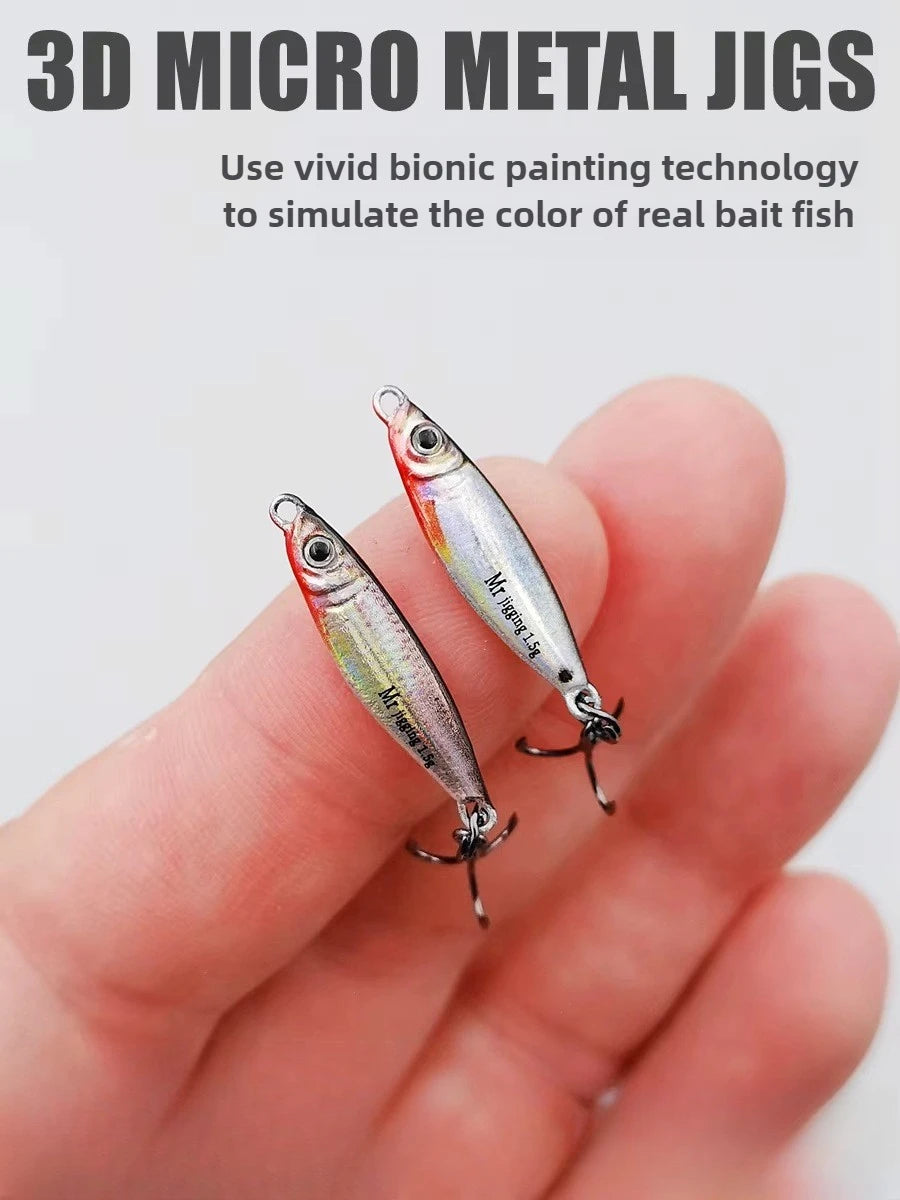 Hand holding two 3D micro metal fishing jigs with realistic bait fish colors and treble hooks.