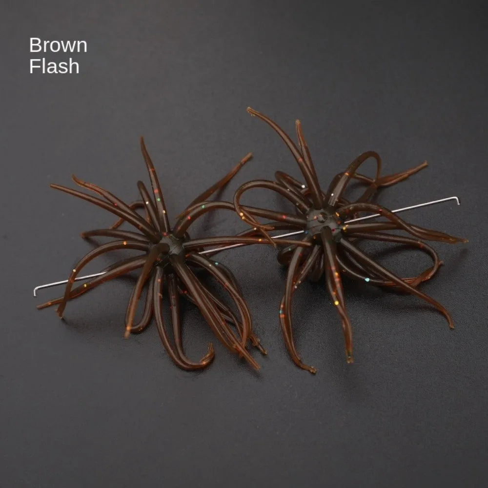 Pair of brown flash silicone fishing lures with multi-leg design on black background.