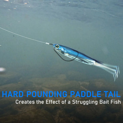 Blue paddle tail fishing lure underwater, mimicking a struggling bait fish above rocks