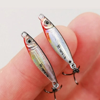 Realistic mini fish-shaped fishing lures with treble hooks held between fingers.