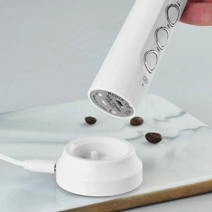 White coffee grinder with coffee beans on a marble surface