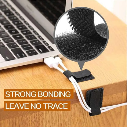 Black hook-and-loop cable straps securing white wires to a wooden desk near a laptop keyboard.