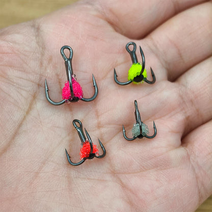 Hand holding four treble fishing hooks with colorful bead bait for outdoor fishing
