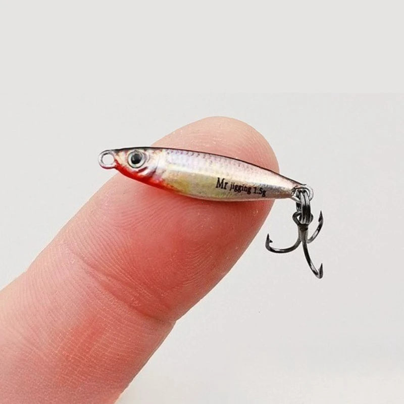 Miniature fishing lure with treble hook balanced on fingertip, outdoor gear accessory