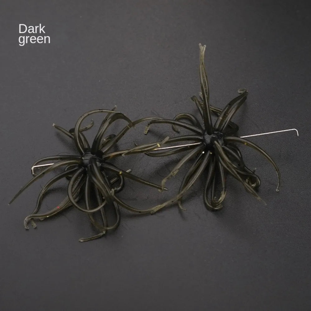 Dark green soft plastic fishing lures with tentacle-like strands and metal hooks on black background.