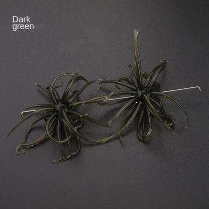 Dark green soft plastic fishing lures with tentacle-like strands and metal hooks on black background.
