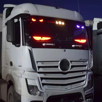 Close-up of a white truck's front grille with visible brand logo at night.