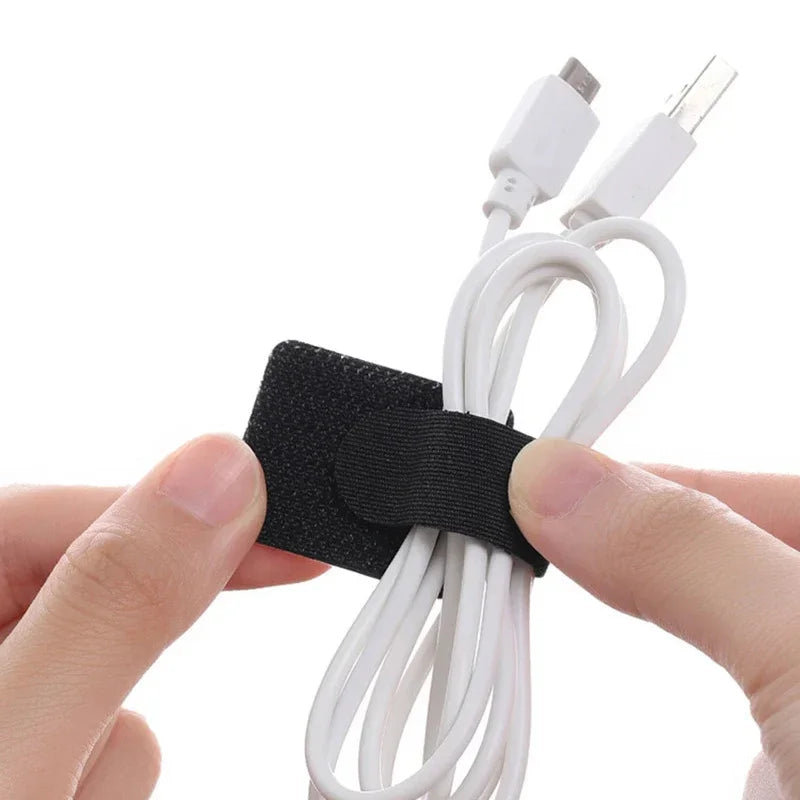Set of black fabric cable straps with hook-and-loop hold gripping white USB cables.