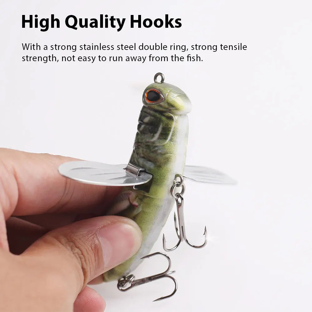 Hand holding lifelike insect fishing lure with metal treble hooks and wings for outdoor fishing.