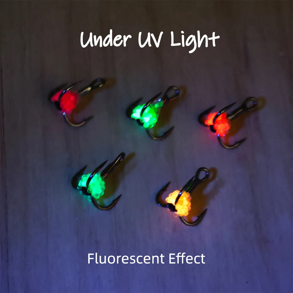 Fluorescent fishing hooks glowing under UV light in green, orange, and red for outdoor use