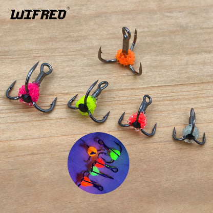 Set of colorful treble fishing hooks with glow-in-the-dark beads on wooden surface