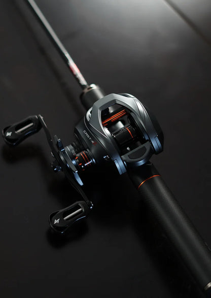 Close-up of a modern black baitcasting fishing reel with orange accents on a dark background