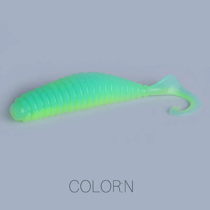 Green soft plastic fishing lure with ribbed body and curled tail on gray background