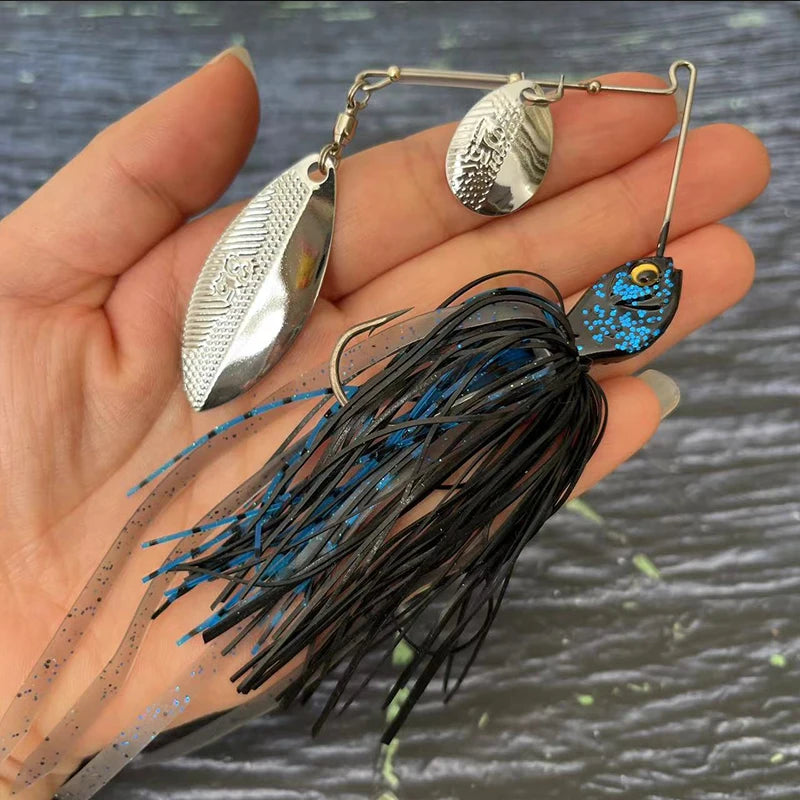 Hand holding a silver and blue spinnerbait fishing lure with metal blades and glitter skirt