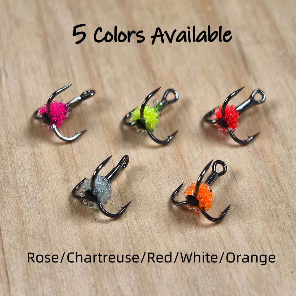 Colorful fishing treble hooks in rose, chartreuse, red, white, and orange on wood surface