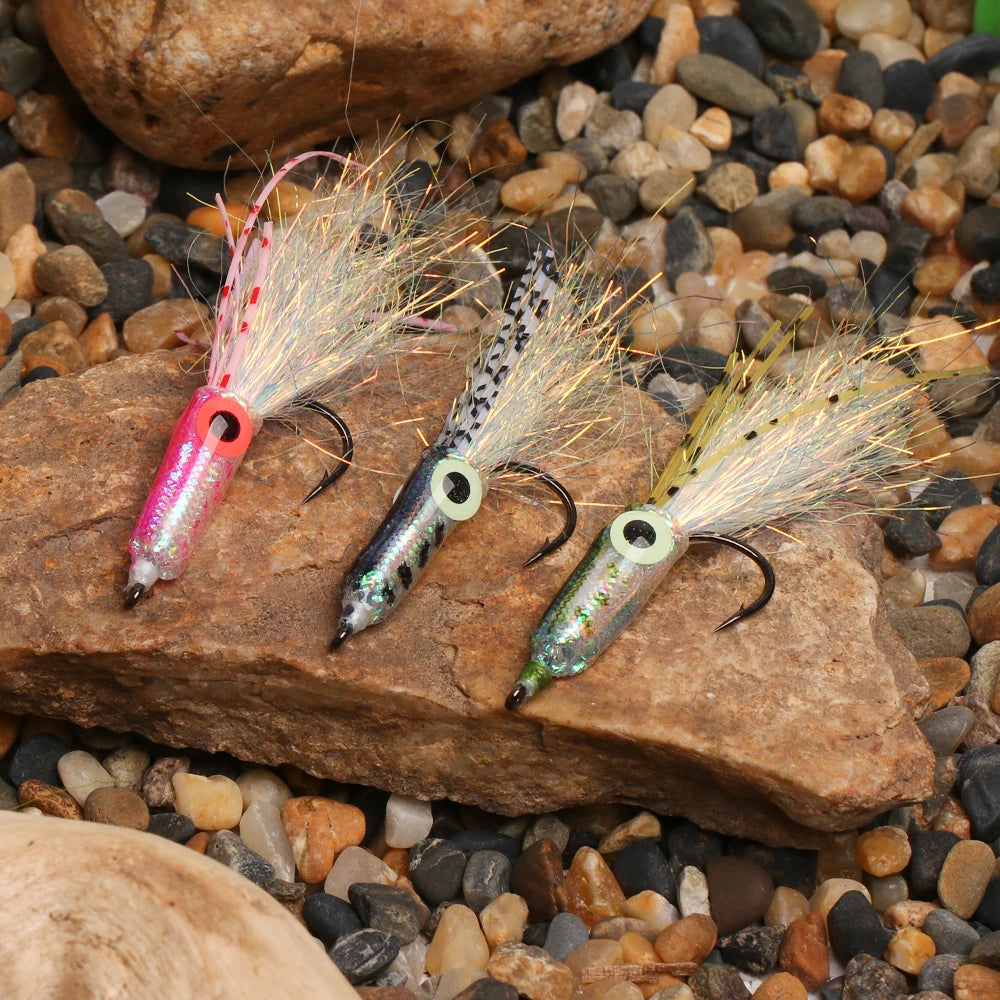 Three colorful fishing lures with hooks on a rock among pebbles, outdoor gear closeup