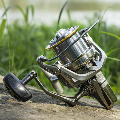 Close-up of a modern spinning fishing reel on a rock, with green grass in the background.