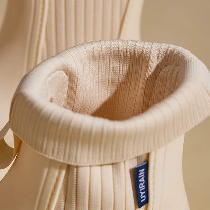 Close-up of a beige knit sock with a brand label on a beige background