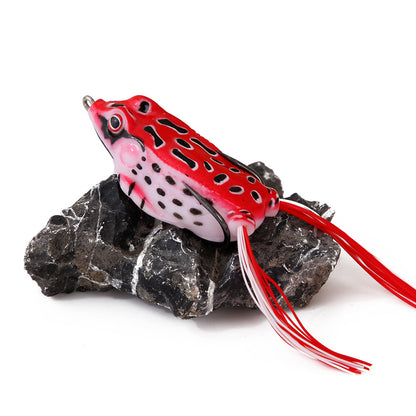 Red and black spotted frog fishing lure with silicone legs on a rock, outdoor gear accessory