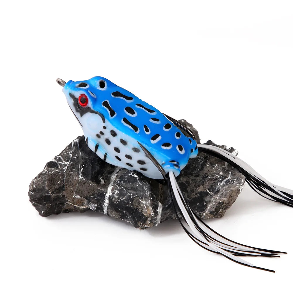 Blue and black spotted frog fishing lure with red eyes on a rock for outdoor angling