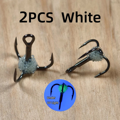 Two white luminous fishing treble hooks with bead accents on wood, UV light effect shown.