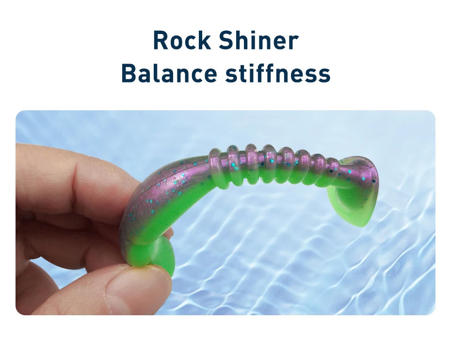 Hand holding green and purple soft plastic fishing lure over water, labeled Rock Shiner.