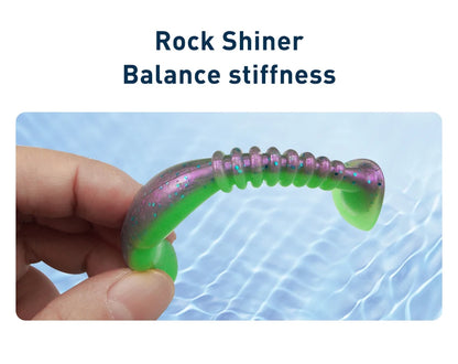 Hand holding green and purple soft plastic fishing lure over water, labeled Rock Shiner.